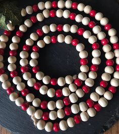 two strands of red and white beaded necklaces on top of a black board