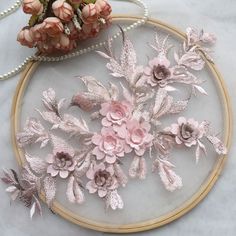 a close up of a embroidery on a table with flowers and pearls in the background