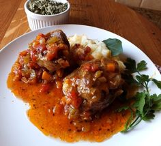 two meatballs and mashed potatoes on a white plate with garnishes