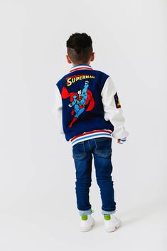 Description: Classic Superman™ Boys Bomber Jacket featuring a vibrant superhero print on the back. Contrasting sleeves with ribbed cuffs and hem for a sporty look. Front zip closure and side pockets for convenience. Ribbed collar adds an extra touch of style. Perfect for keeping warm while showcasing your favorite superhero. Material & Care: Fabric: High-quality polyester and cotton blend. Care Instructions: Machine wash cold with like colors. Tumble dry low. Do not bleach. Iron on low heat if n Classic Superman, Superman Boy, Jacket With Patches, Grey Long Sleeve Shirt, Baby Boy Onesies, Blue Sweatshirt, Sporty Look, Romper With Skirt