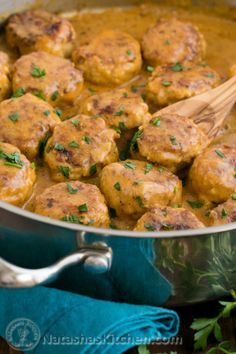 meatballs and gravy in a pot with a wooden spoon