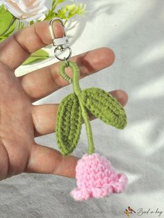 a hand holding a crocheted keychain with a flower attached to it