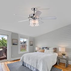 a bedroom with white walls and wood floors has a ceiling fan that lights up the room