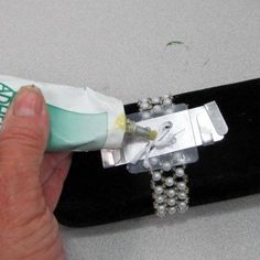 a person holding a toothbrush in their left hand with pearls on it and a tube of toothpaste next to the brush