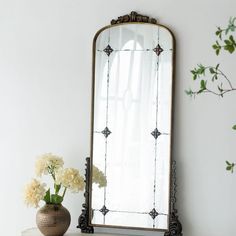 a mirror sitting on top of a table next to a vase with flowers