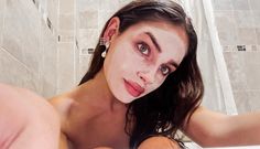 a woman with white makeup is taking a selfie in the bathroom