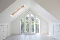 an empty room with white walls and wooden flooring is shown in the middle of this attic