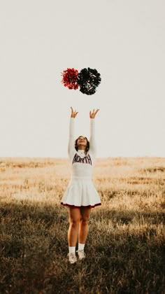 a girl in a cheerleader outfit is holding up her pom - poms