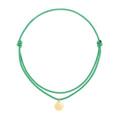 a green cord bracelet with a gold disc charm on the end and a white background