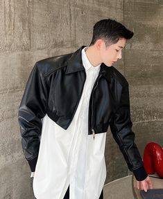 a young man wearing a black leather jacket and white shirt