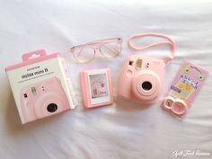 a pink camera and some other items on a bed