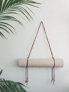 a white wall hanging on a rope with a potted plant in the corner behind it