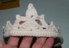 a hand holding a crocheted white crown