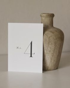 a white card with the number one on it next to a vase and a paper