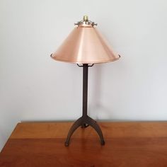 a lamp sitting on top of a wooden table next to a white wall and floor