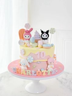 a pink and yellow cake with two small animals on it's top that says happy 10th