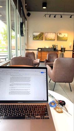 an open laptop computer sitting on top of a white table in front of a window