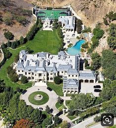 an aerial view of a large mansion with a pool in the front yard and trees surrounding it