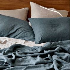 an unmade bed with blue sheets and pillows