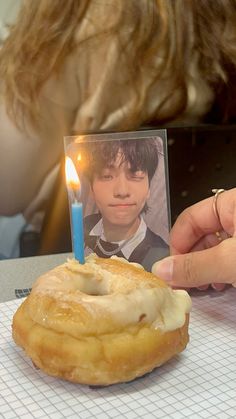 a person lighting a candle on top of a doughnut with a photo in the middle