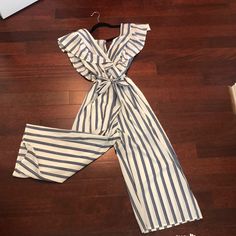 V-Neck Front With Shoulder Ruffles, Tie For The Waist. Striped V-neck Jumpsuits And Rompers For Summer, Casual Ruffled V-neck Jumpsuits And Rompers, White V-neck Jumpsuit With Ruffles, Striped Jumpsuits For Spring Day Out, Summer Jumpsuit With Ruffles And V-neck, White Ruffled Jumpsuits And Rompers For Vacation, Summer Jumpsuit With V-neck And Ruffles, Summer V-neck Jumpsuit With Ruffles, Summer V-neck Ruffles Jumpsuits And Rompers