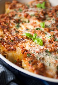 a casserole dish with meat and cheese covered in parmesan, basil leaves