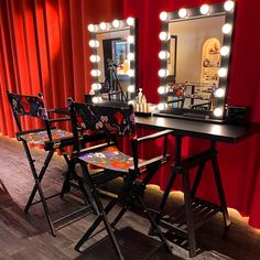 two chairs are sitting in front of a vanity with lights on it and a mirror behind them