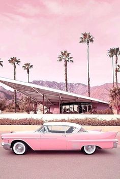 an old pink car parked in front of a palm tree covered building with a solar panel on the roof