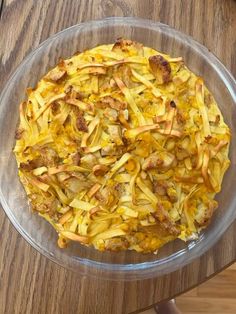 a glass bowl filled with pasta on top of a wooden table