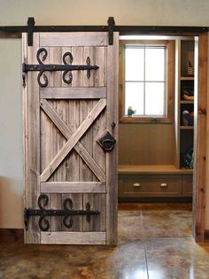 an open barn door with iron hardware on the outside and inside, in front of a window