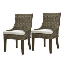 pair of brown wicker chairs with white cushions on the back and side, facing each other