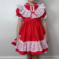 "Frilly full circle skirt red dress with white lace trim that is perfect for twirling. The red fabric has a shiny tiny polka dot weave. The skirt is lined with a white layer. It buttons up the back and there is an attached tie belt.  Brand - Mini World Content - 80% Polyester 20% Rayon  Size - Labeled Size 4 but it fit my average size 5 year old with a little room to grow so please check all measurements to insure fit Shoulders - 10\" across Chest - 12\" pit to pit  Sleeves - 5.75\" from shoulder seam Waist - 11.5\" across Length - 22\" (9.75\" bodice, 12.25\" skirt) Condition - I don't see any flaws" Retro Red Dress For Costume Party, Red Vintage Victorian Dress With Ruffles, Retro Red Ruffled Dress, Retro Red Dress With Ruffles, Red Vintage Dress With Lace Trim, Vintage Red Dress With Lace Trim, Frilly Dress, Mini World, Frilly Dresses