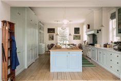 a large kitchen with white cabinets and wooden floors