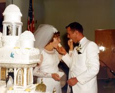 a bride and groom are feeding each other wedding cake while standing in front of an american flag