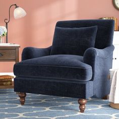 a blue chair sitting on top of a rug next to a table with a clock