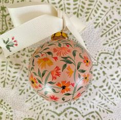 an ornament with flowers painted on it and a ribbon tied around the top