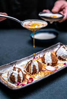 a person is pouring sauce on some desserts