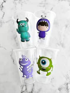 three plastic cups with monsters on them sitting on a marble counter top next to each other