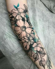 a woman's arm with flowers and leaves on it