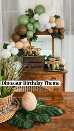 a table topped with lots of balloons and greenery next to a basket filled with plants