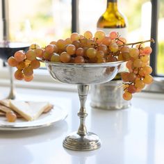 some grapes are in a silver bowl on a table