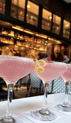 three glasses filled with pink liquid sitting on top of a table next to each other