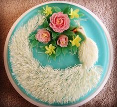 a cake decorated with flowers and feathers on a blue plate in the shape of a crescent