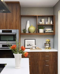 a kitchen with an oven, microwave and counter top in the center is decorated with orange flowers