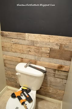 a white toilet sitting inside of a bathroom next to a wooden paneled accent wall