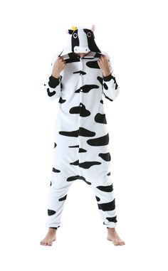 a person in a cow costume standing on one leg and covering his face with the other hand