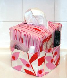 a pink and white flowered tissue box with tissues in it on a counter top