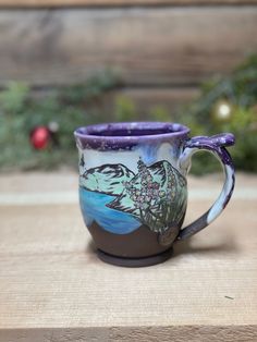 a purple and white coffee cup sitting on top of a wooden table