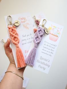 two tasseled key chains are being held by a woman's hand with a birthday card