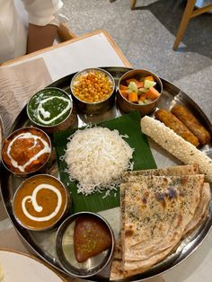 a metal plate topped with lots of different types of food on top of a table